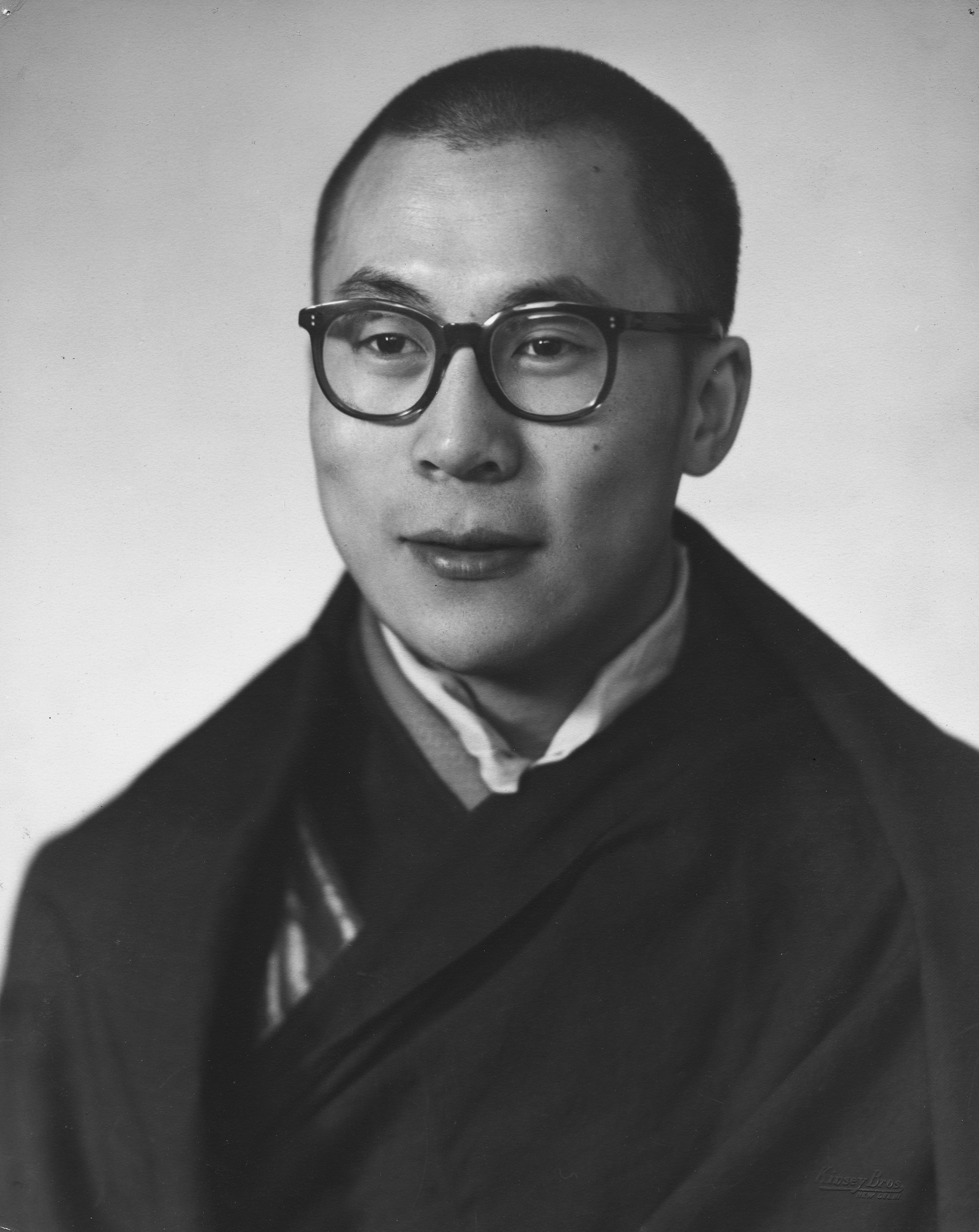 年轻的达赖喇嘛，戴着黑框眼镜，穿着长袍